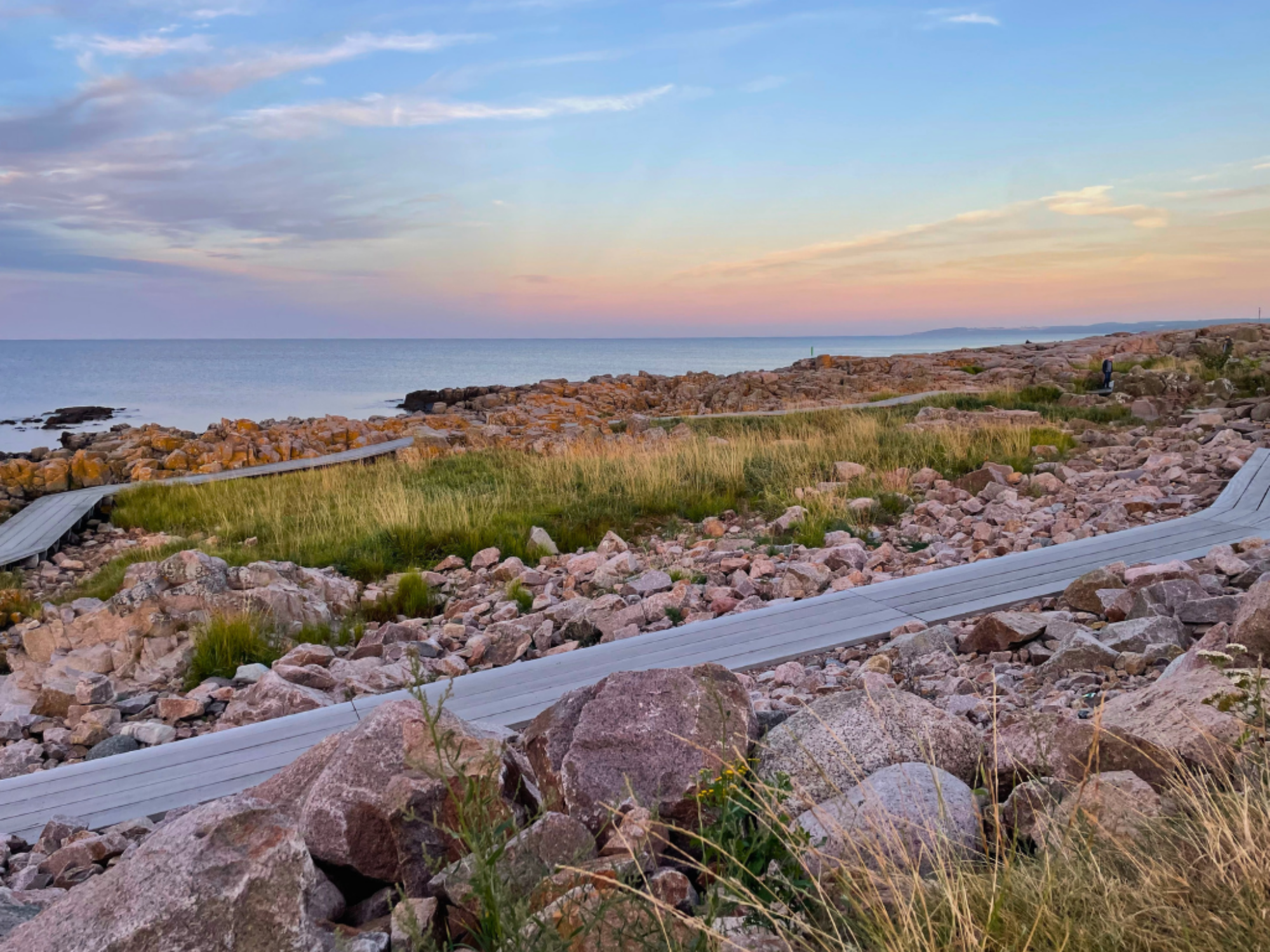 Stenstrand med plankesti i solnedgang på Bornholm